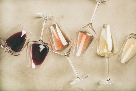 Red, rose and white wine in glasses over grey background