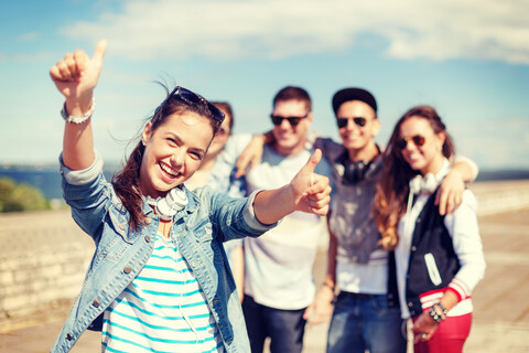 teenage girl with headphones and friends outside