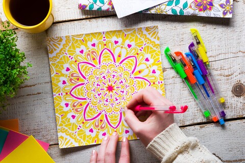 52232533 - woman coloring an adult coloring book, new stress relieving trend, mindfulness concept, hand detail